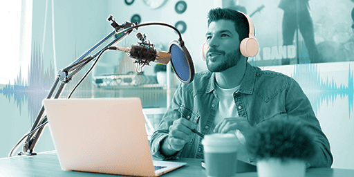 podcaster in his natural element with mic, wind screen, headphones, computer, etc.