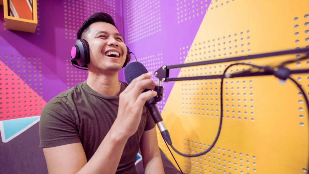 2 - Official Libsyn Blog Young man talking into a mic with headphones on smiling