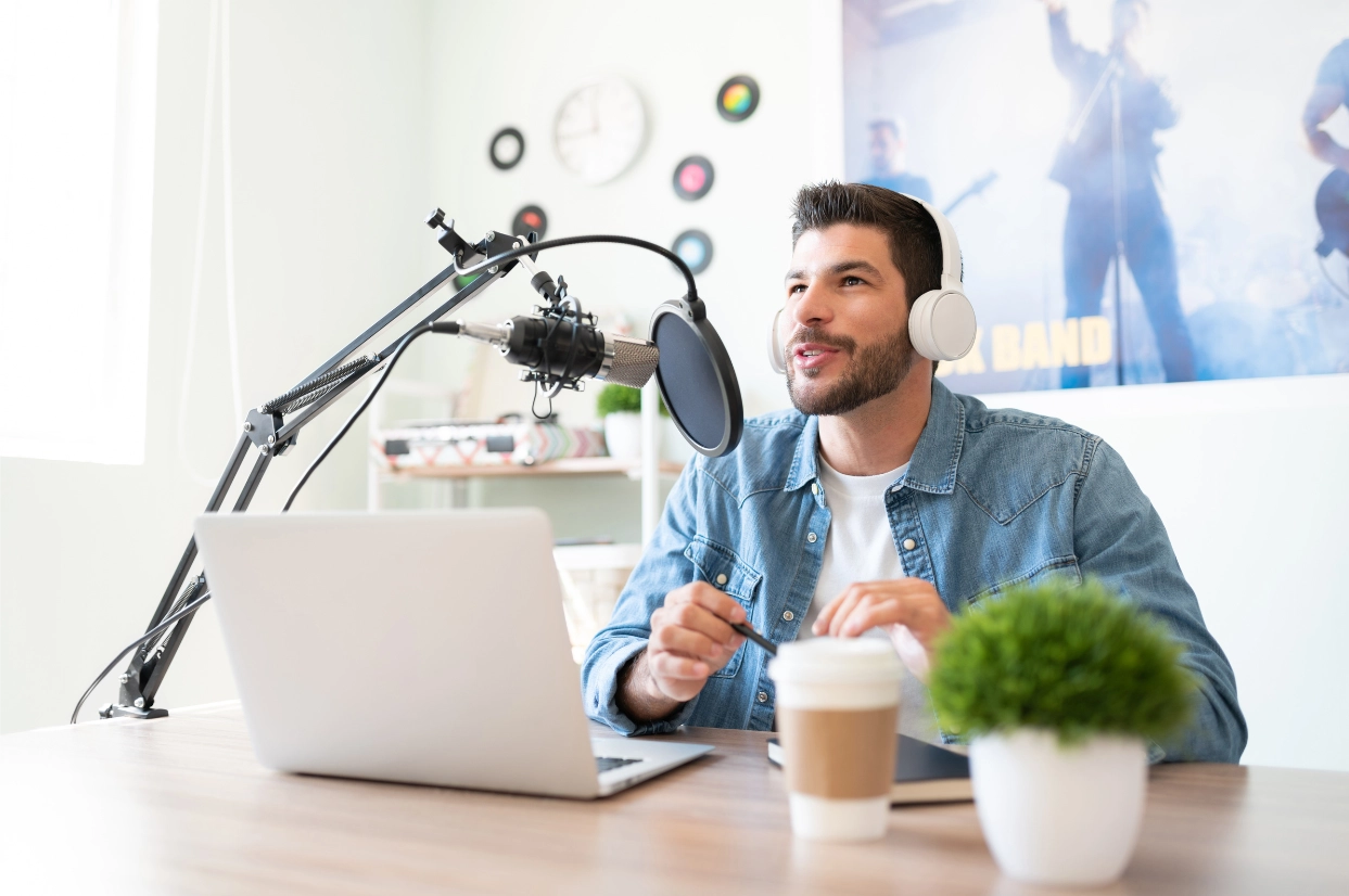 Man podcasting with microphone, headset, and laptop.